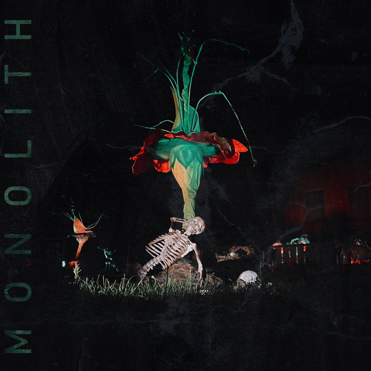 MONOLITH cover art: a skeleton beneath a glowing red and teal flower in the dark
